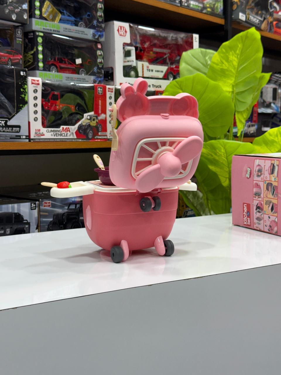 Pink toy suitcase with pig design on a shelf with toys in the background